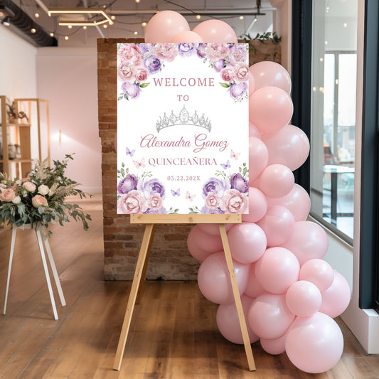 Decorative setup with a 'Pink Floral and pearls Welcome' sign for a Quinceañera event, surrounded by pink balloons and flowers.