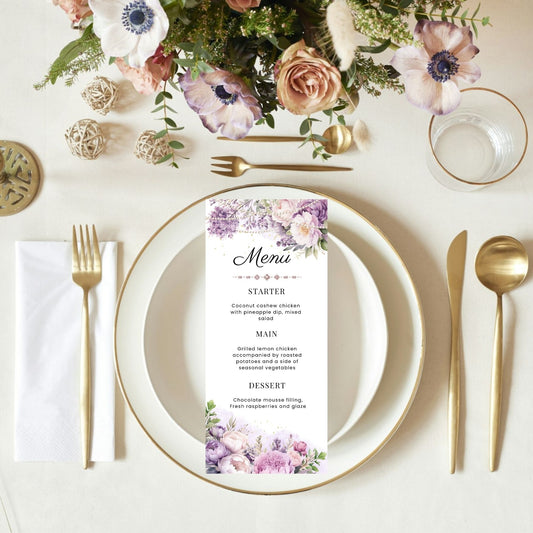 Table setting with Purple and pearls floral menu card, plates, cutlery, and flowers on a white tablecloth.
