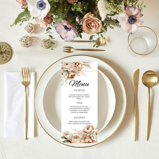 Elegant table setting with boho floral ans pearls menu card, plates, and cutlery on a white surface.