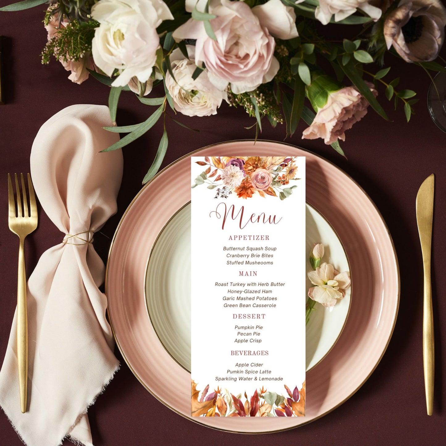 Table setting with a floral menu card on a plate, pink napkin, and gold cutlery.