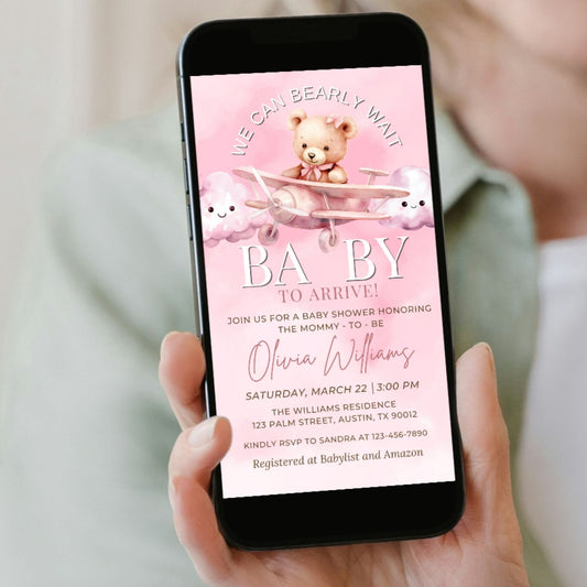 Phone displaying a baby shower invitation with teddy bears on a pink background
