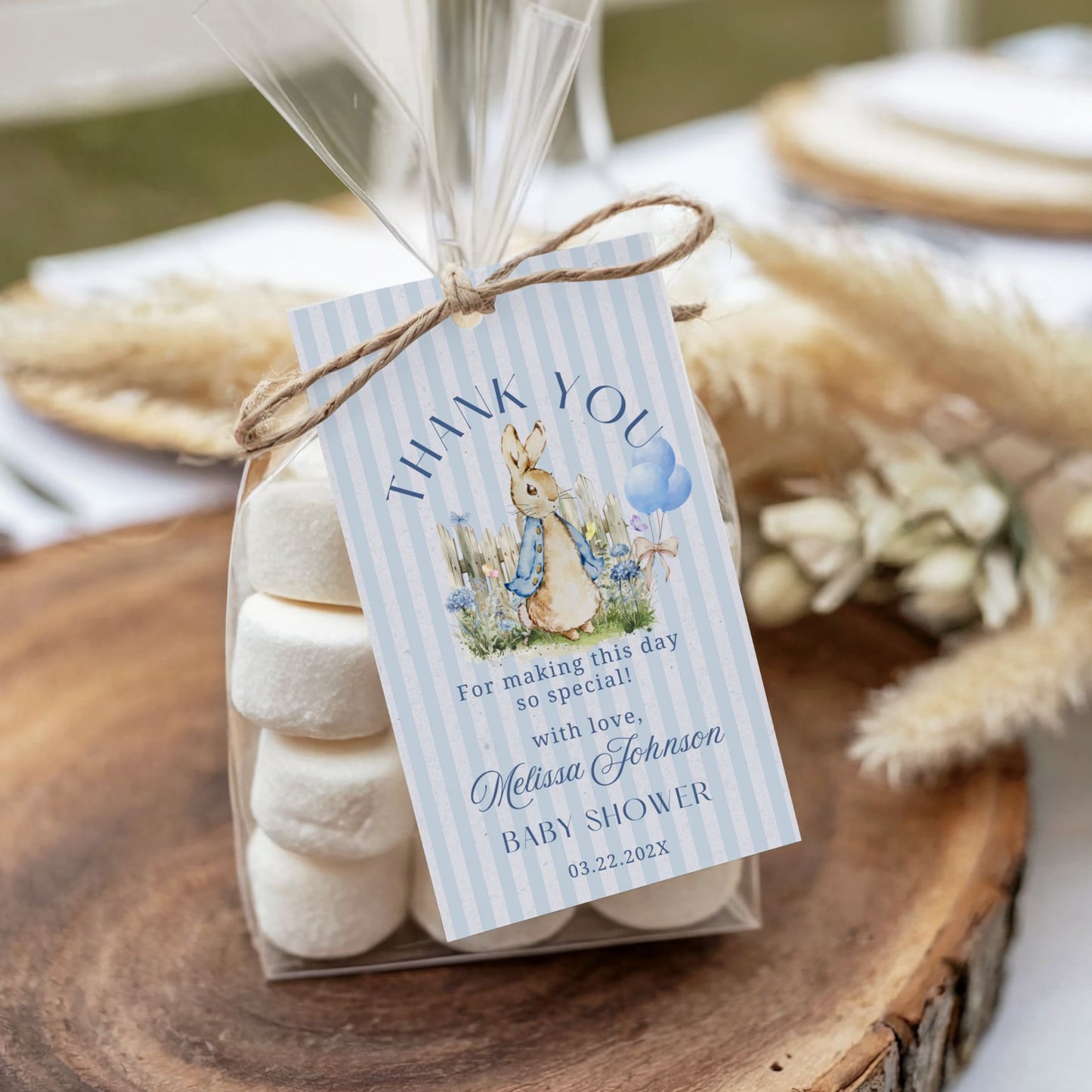 Packaged marshmallows with a 'thank you' tag for a baby shower on a wooden surface.