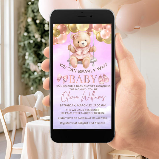 Hand holding a smartphone displaying a baby shower invitation with a teddy bear graphic.