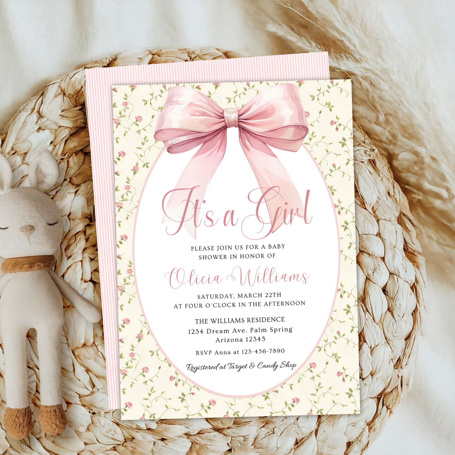 Baby shower invitation with pink bow on a decorative surface