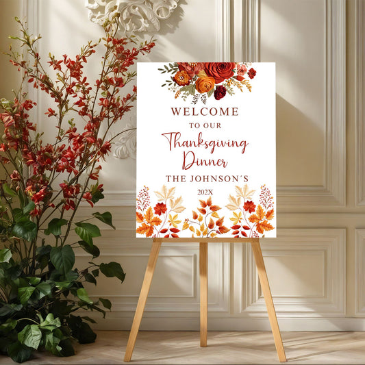 Thanksgiving dinner sign with floral design on an easel next to decorative plants.