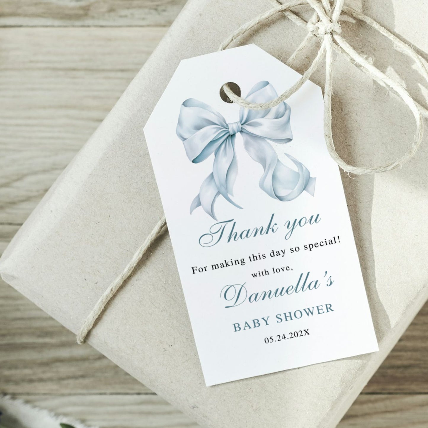 Gift tag with blue bow on a wrapped gift with string, on a wooden surface.