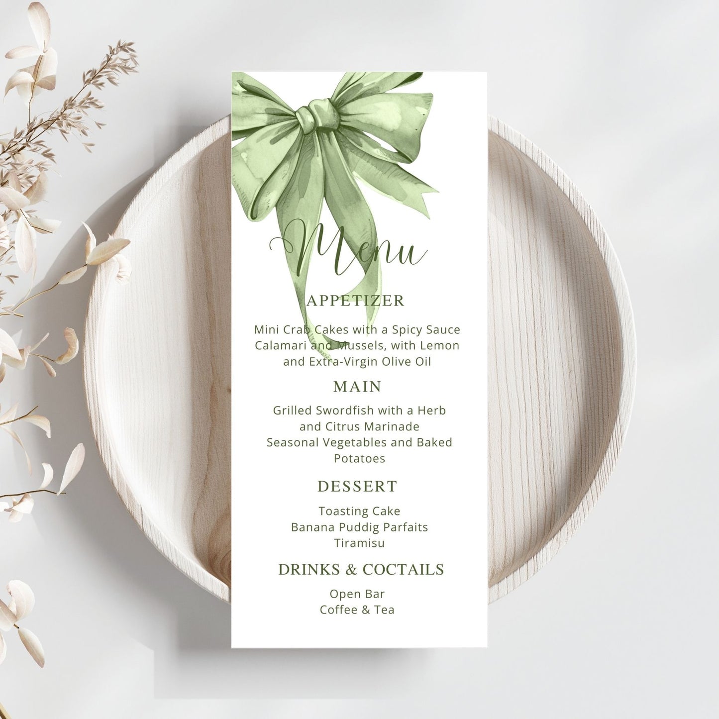 Menu card with a sage green bow design on a white plate with wooden rim