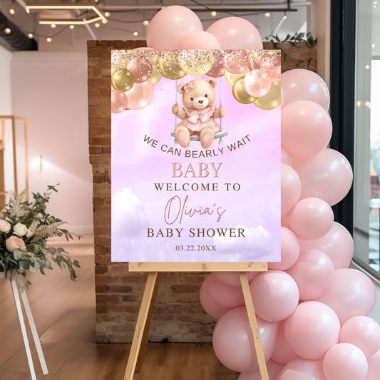 Baby shower sign with teddy bear graphic and pink balloons in a room setting