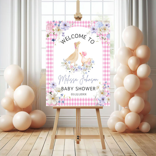 Baby shower welcome sign on an easel with balloons in a room.
