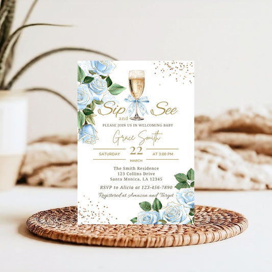 Baby shower invitation with floral design and champagne glass on a woven mat.