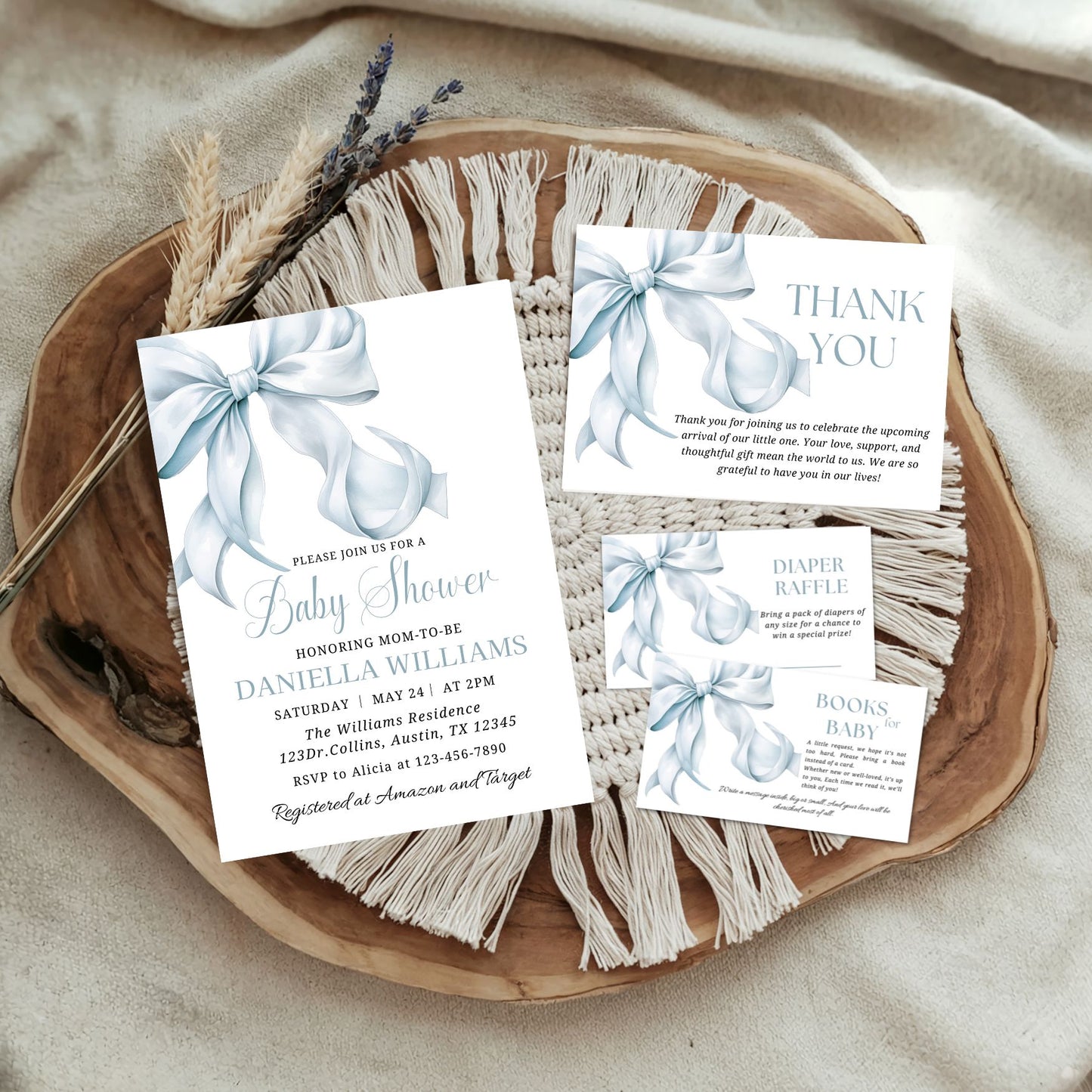 Baby shower invitation set with blue bows on a wooden tray.