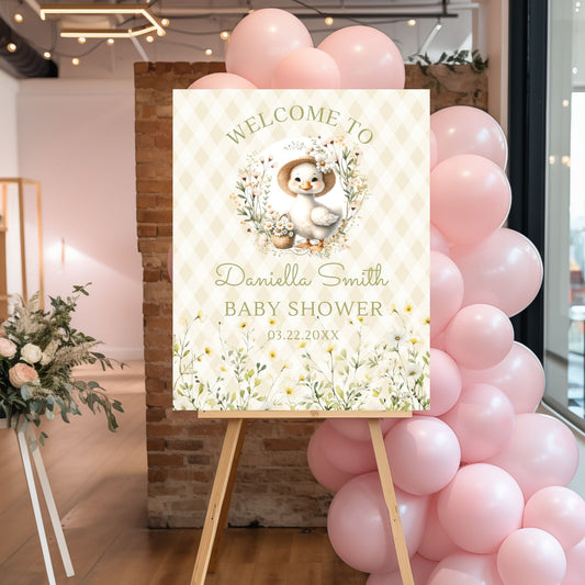 Baby shower welcome sign with pink balloons and floral decorations.