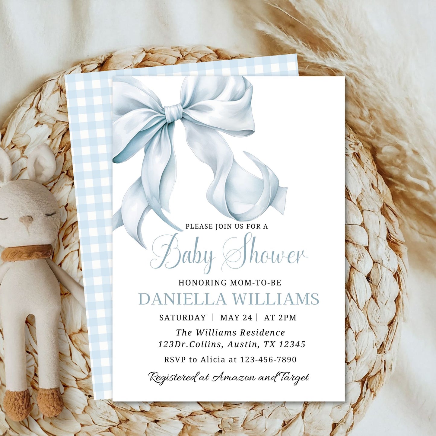 Baby shower invitation with a blue bow on a textured surface