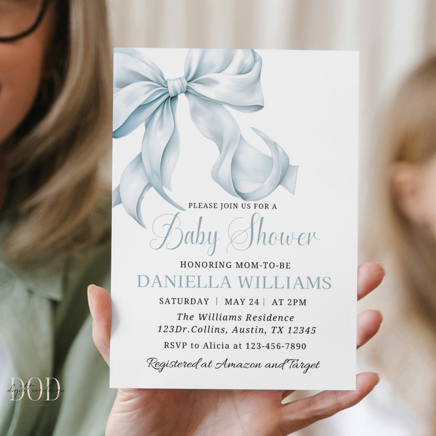 Baby shower invitation with blue ribbons held by a person
