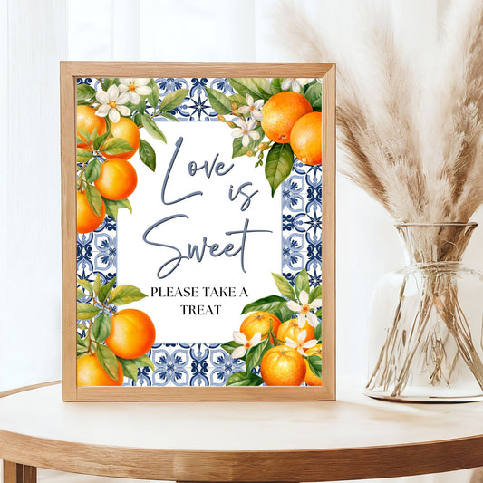 Framed artwork with Mediterranean and oranges and floral design on a table, with text "love is sweet"
