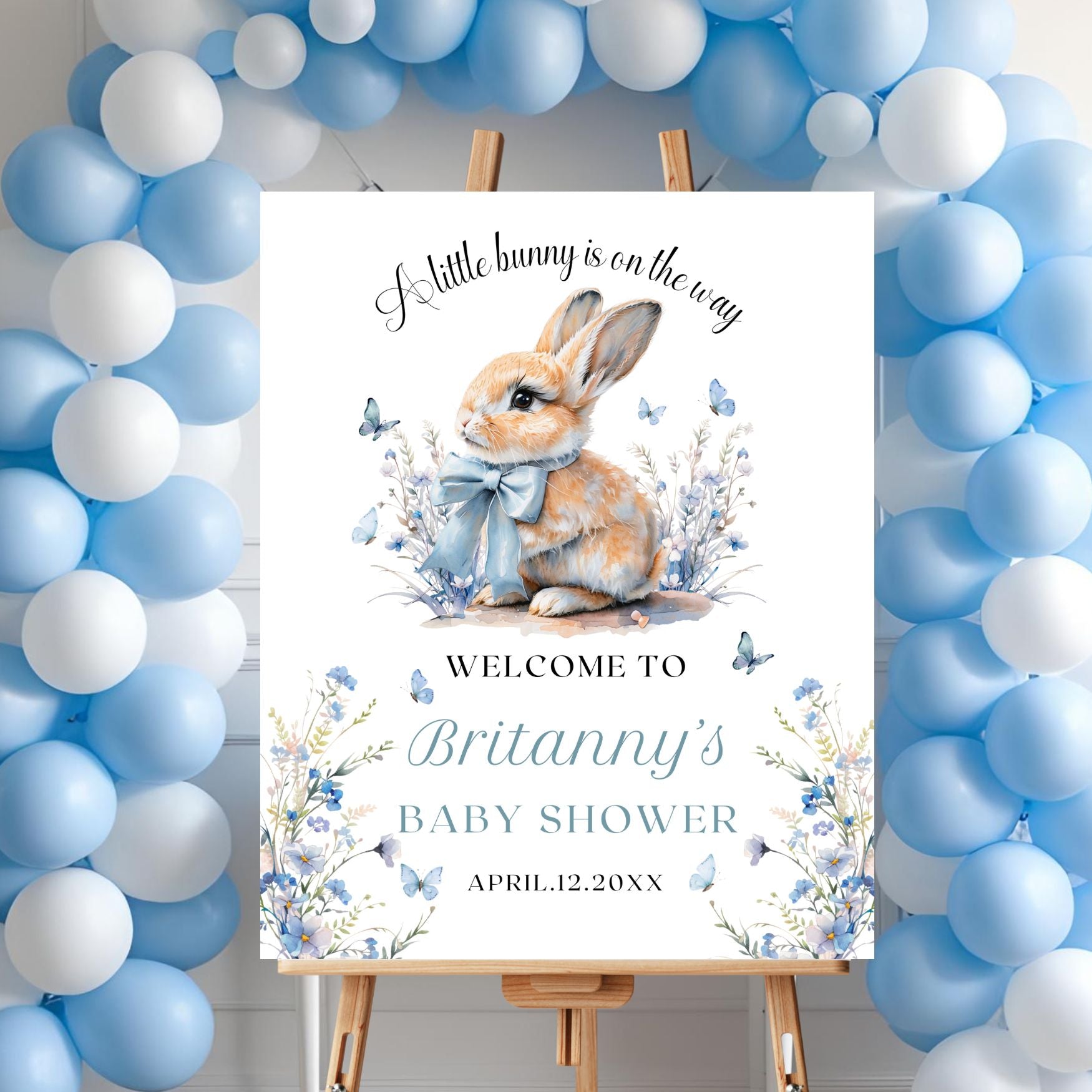 Baby shower invitation with a bunny illustration surrounded by blue and white balloons.