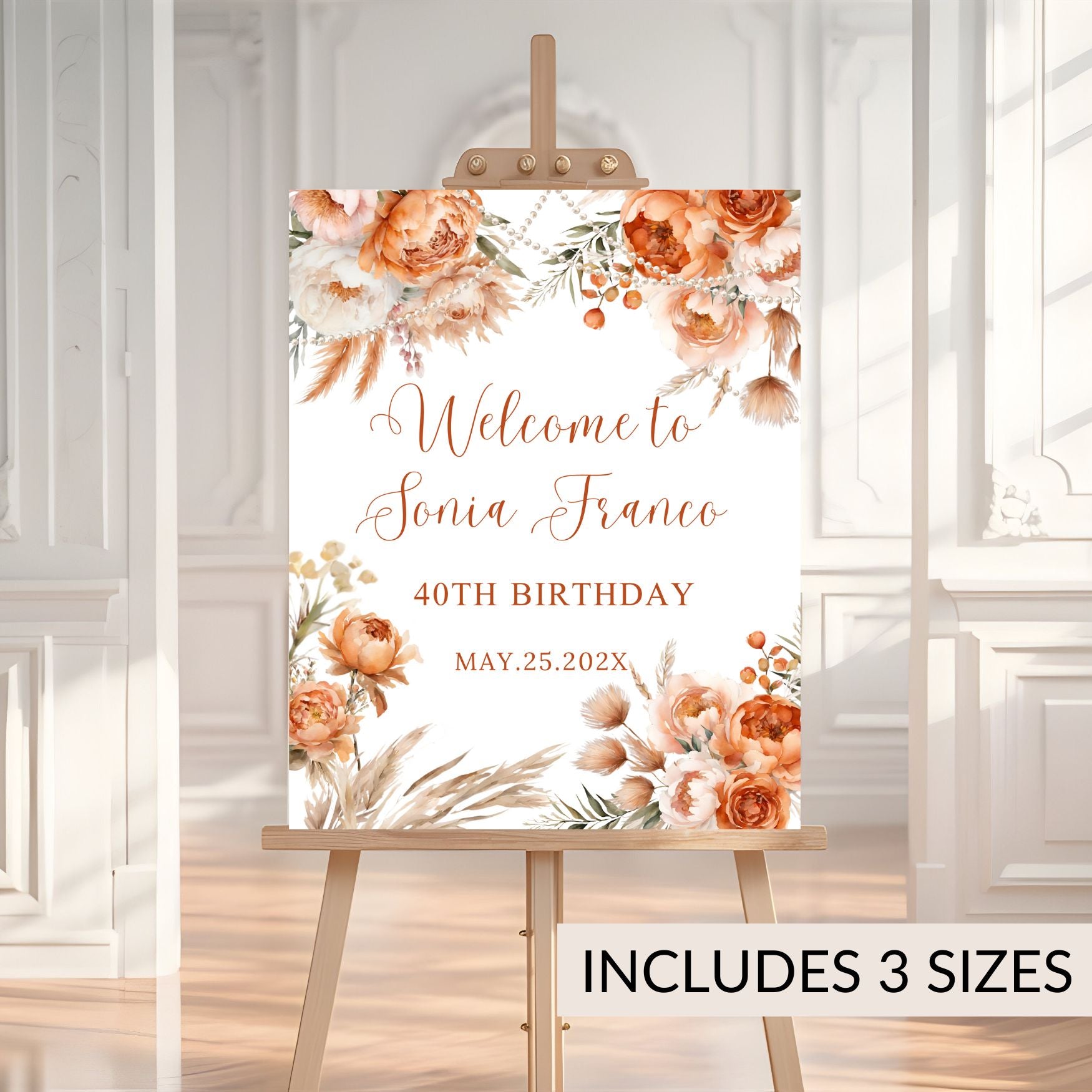 Decorative birthday sign with coral floral design on an easel against a white wall.