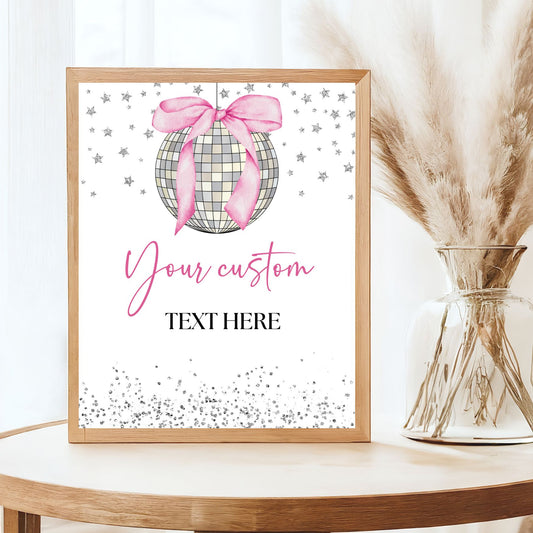 Framed decorative print with a pink bow Disco Ball and customizable text on a white background, placed on a wooden surface.