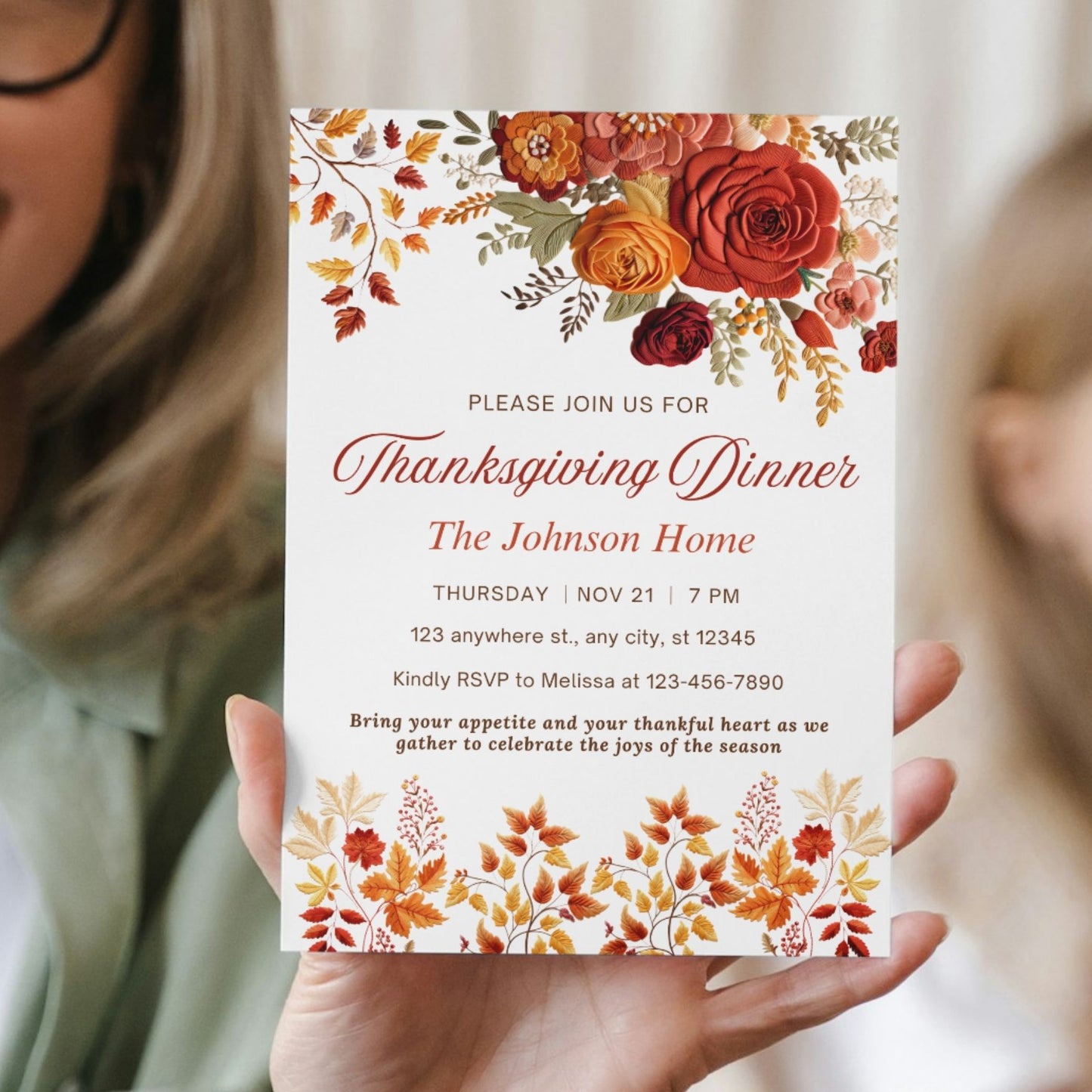 Invitation card for Floral Thanksgiving dinner held by a person with autumn-themed design
