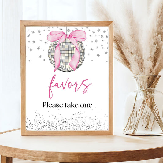 Framed decorative sign with a plaid Silver Disco ball and pink bow, placed on a table with a vase of dried plants.