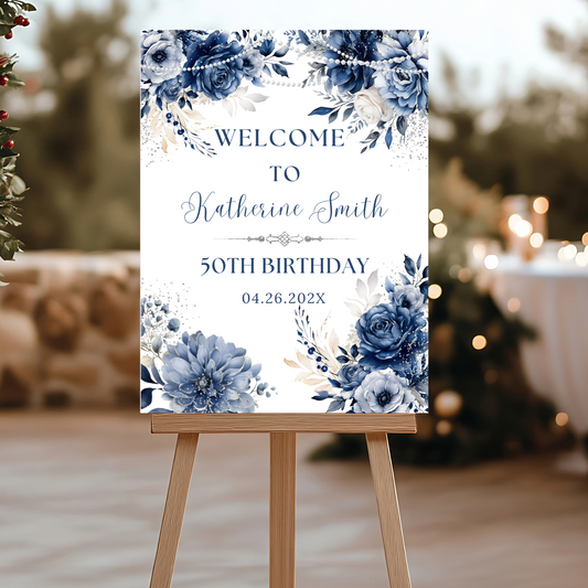 Decorative birthday welcome sign with blue floral design on an easel.