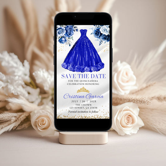 Phone displaying a royal blue dress save the date invitation with flowers on a stand, surrounded by white roses.