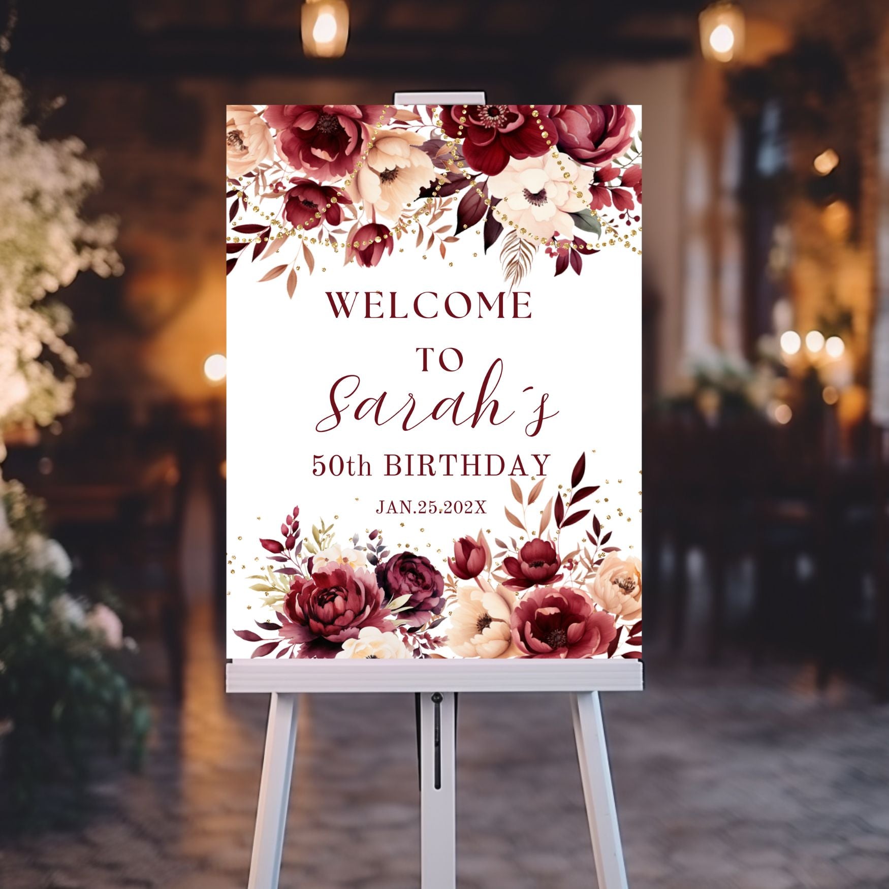 Decorative birthday welcome sign with Burgundy floral design on an easel against a blurred indoor background.
