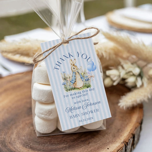 Packaged marshmallows with a 'thank you' tag for a baby shower on a wooden surface.