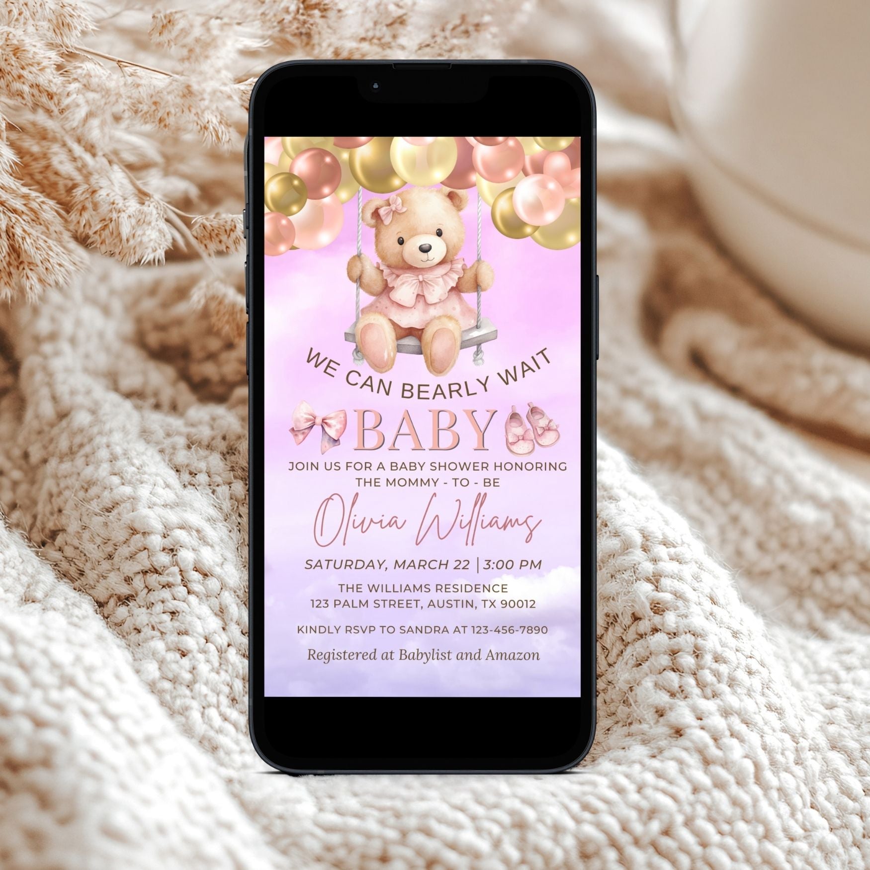 Phone displaying a baby shower invitation with a Pink teddy bear design on a textured surface