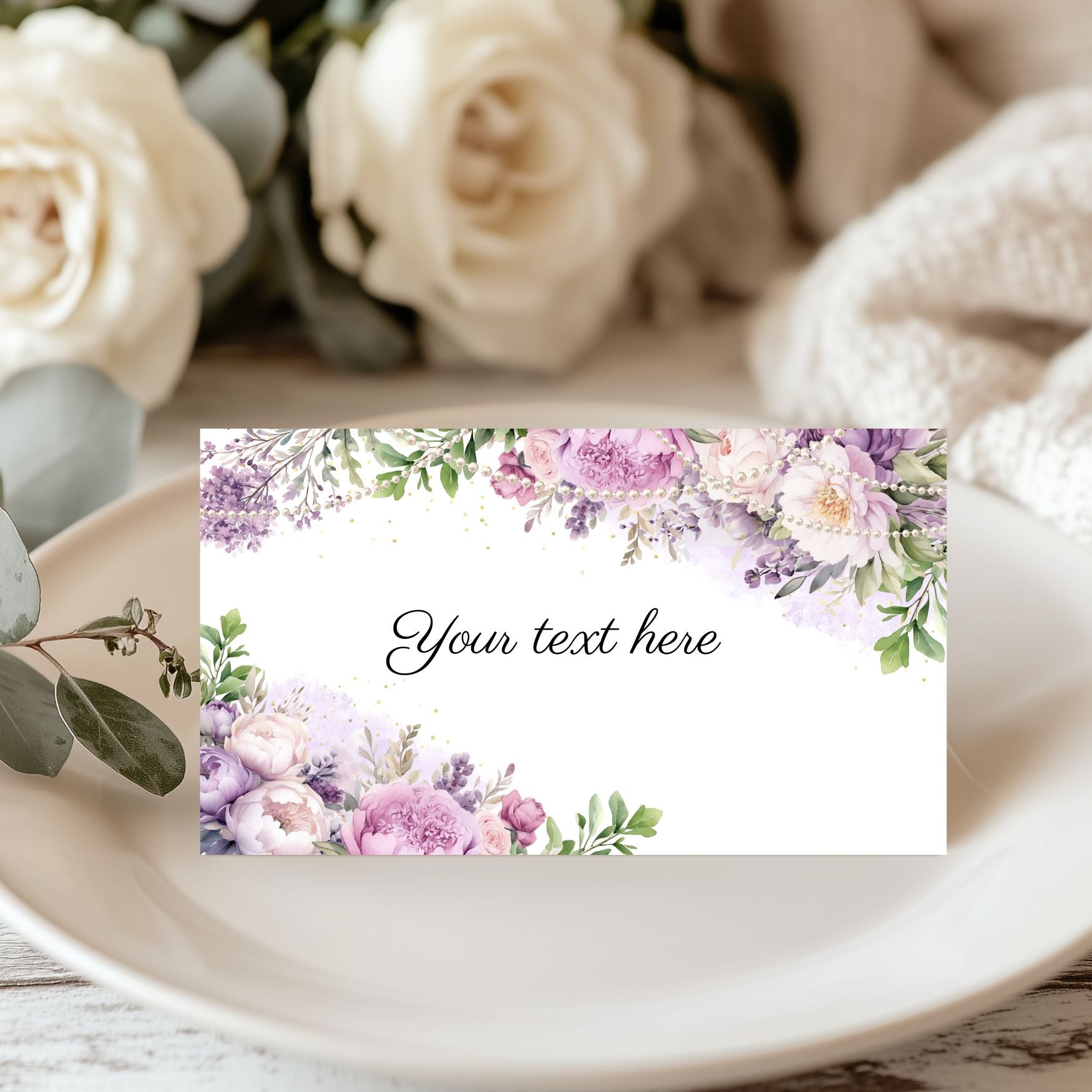 Purple floral and pearls  card with placeholder text on a table with flowers