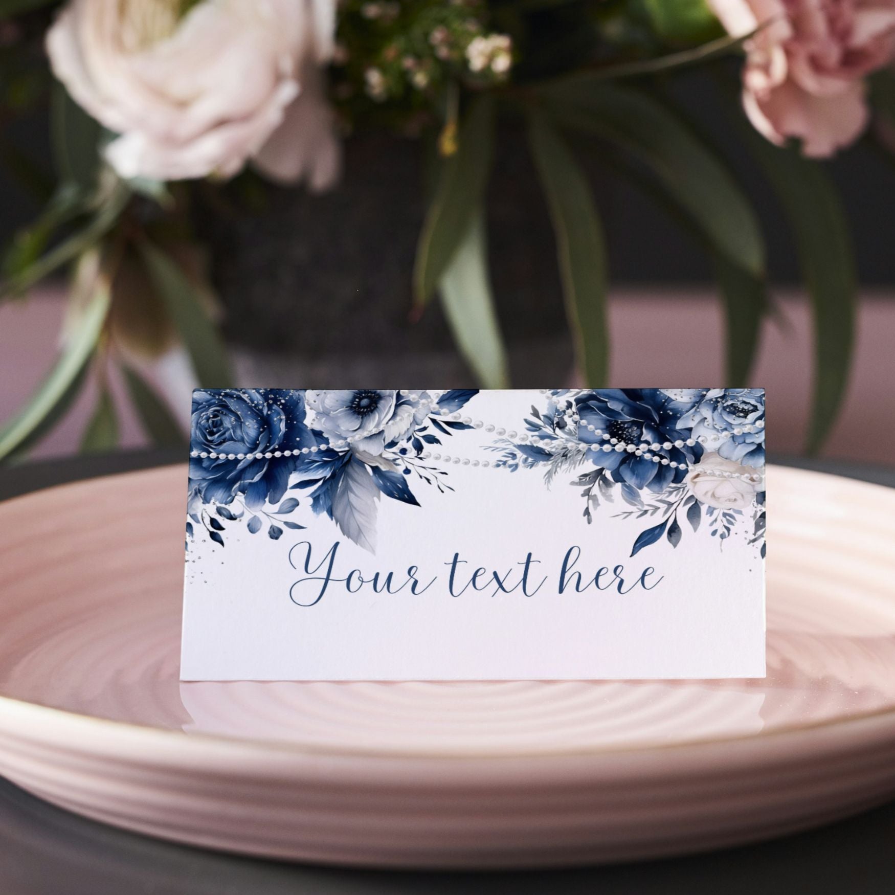 Blue Floral and pearls place card with 'Your text here' on a pink plate with flowers in the background
