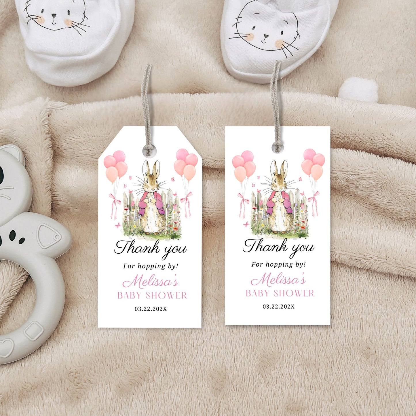 Baby shower favor tags with bunnies and balloons on a soft fabric background