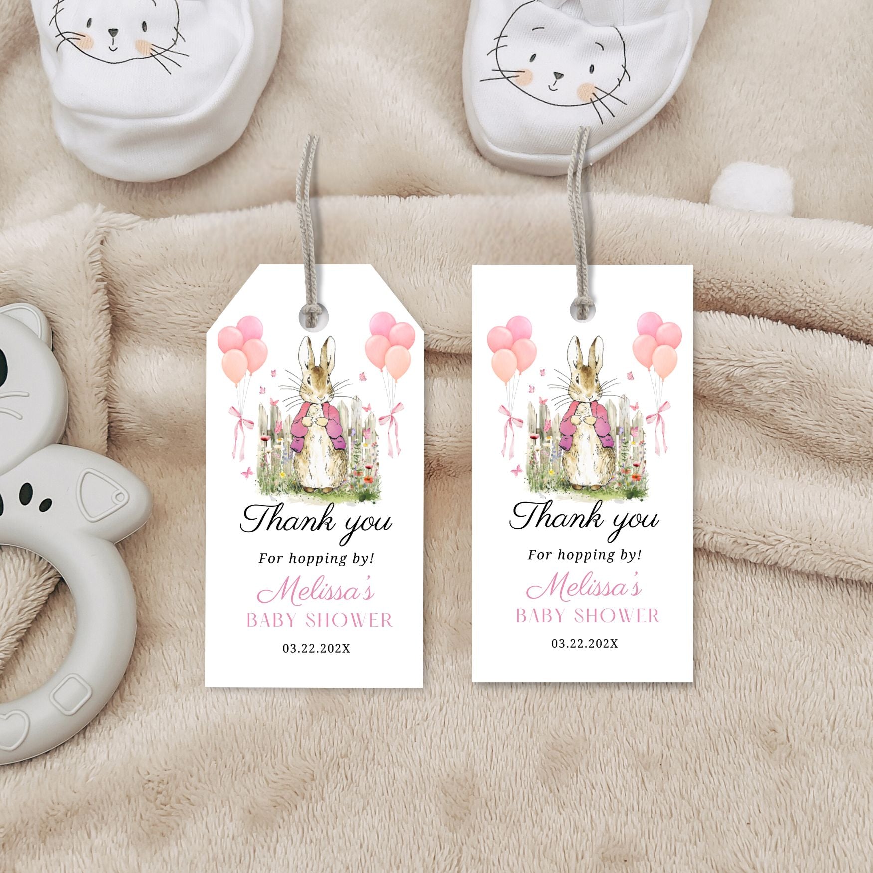 Baby shower favor tags with bunnies and balloons on a soft fabric background
