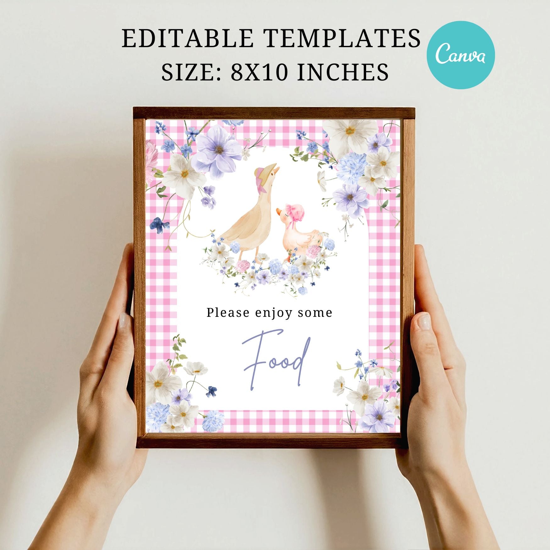 Framed print with floral design and text held by hands, on a plain background