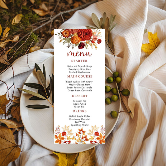 Embroidered effect floral Menu card with autumn-themed design on a white plate surrounded by fall leaves and branches.
