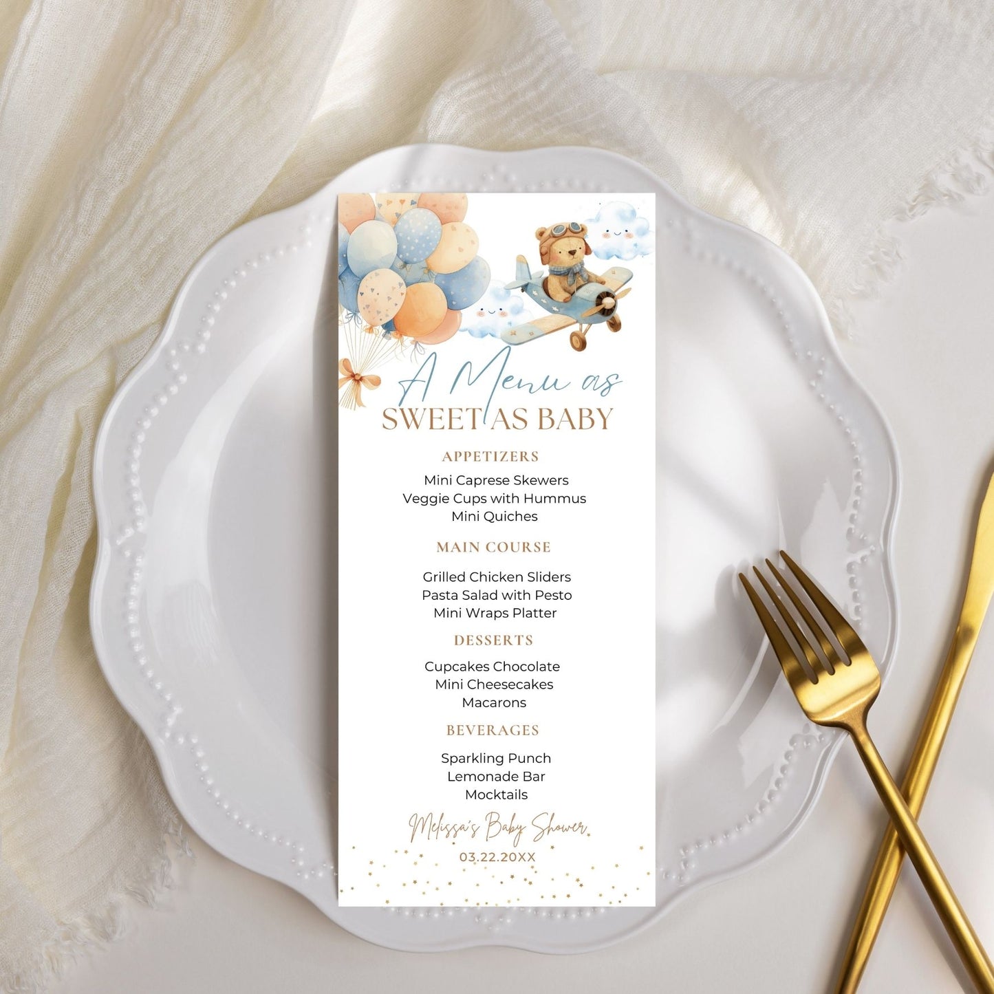 Menu card for a baby shower on a white plate with a gold fork.