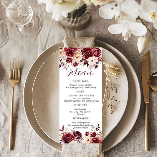Burgundy Menu card with floral design on a table setting with plates, cutlery, and flowers.