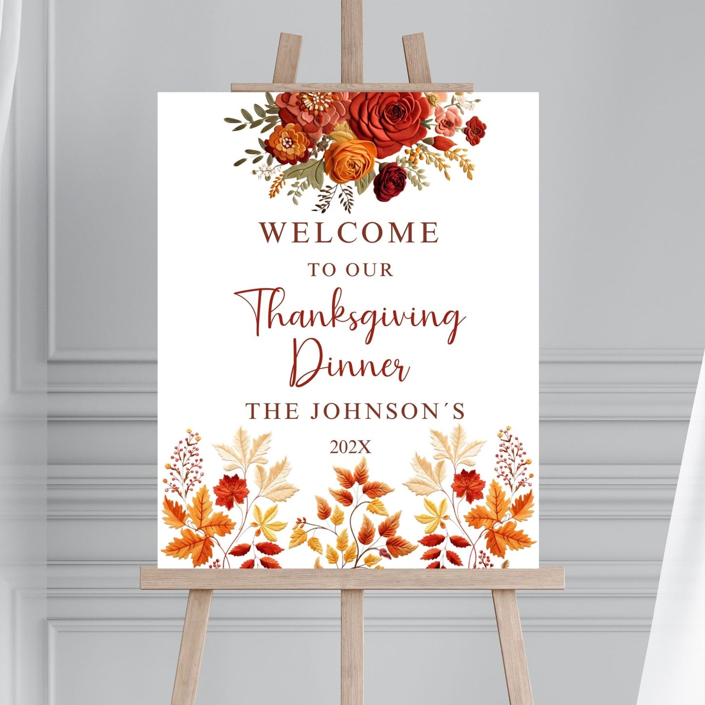 Thanksgiving dinner welcome sign with fall floral design on an easel against a gray background