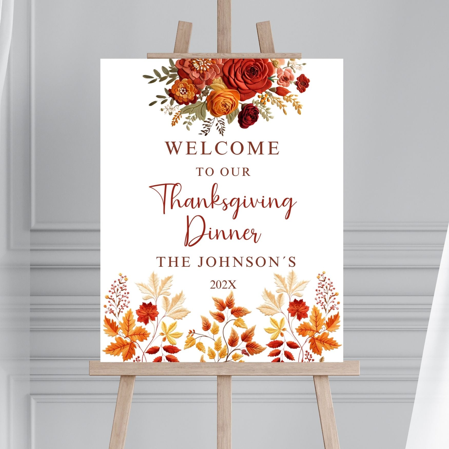 Thanksgiving dinner welcome sign with fall floral design on an easel against a gray background