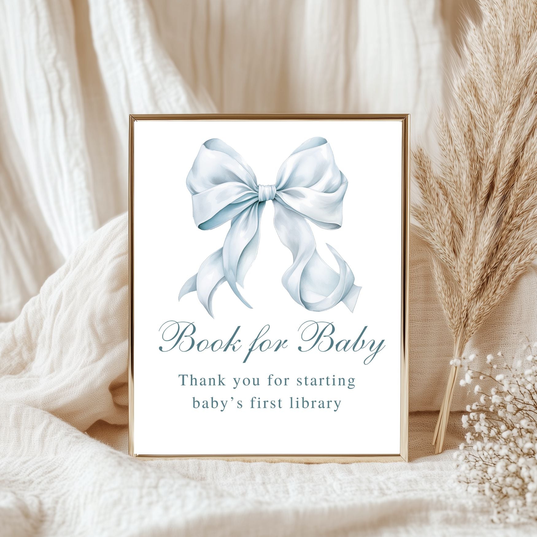 Framed print with a blue bow and text on a soft fabric background