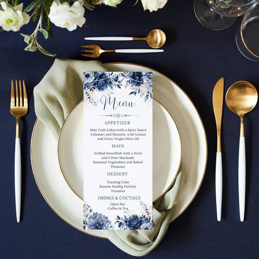 Dining table setting with navy floral menu card, plates, and cutlery on a dark surface