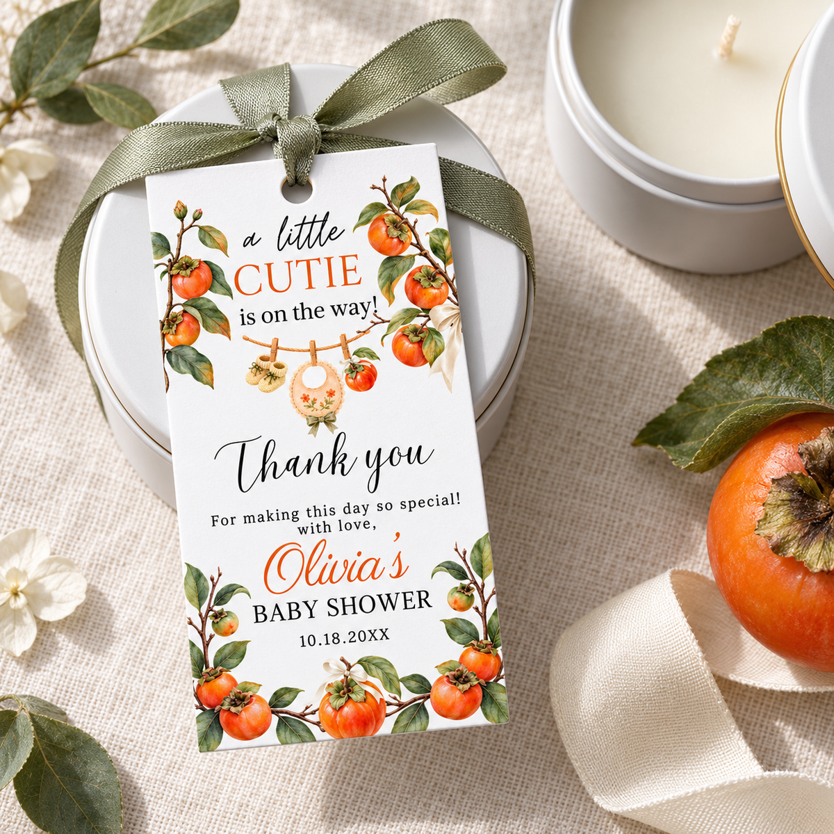 A Little Cutie Persimmon Baby Shower Thank You Gift Tag on a gift box with greenery and satin ribbon.