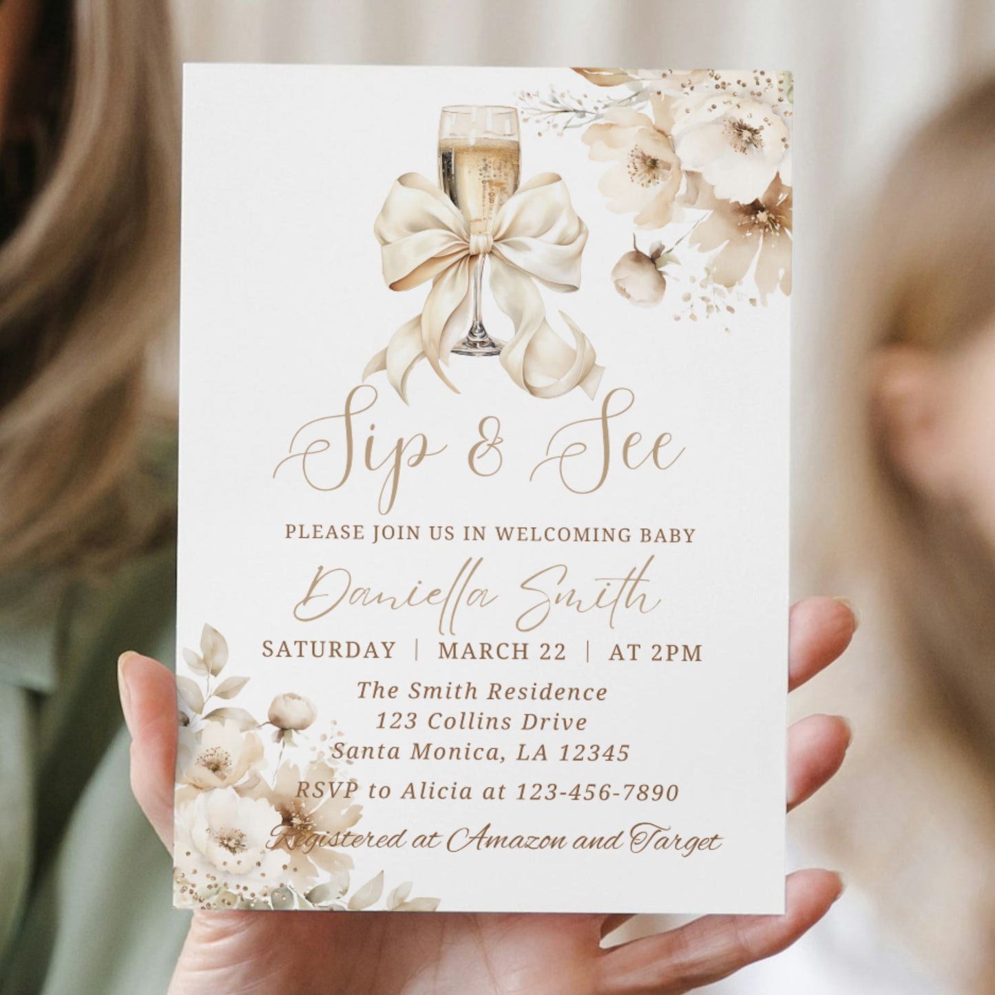 Invitation card with champagne glass, bow, and floral design held by a person.
