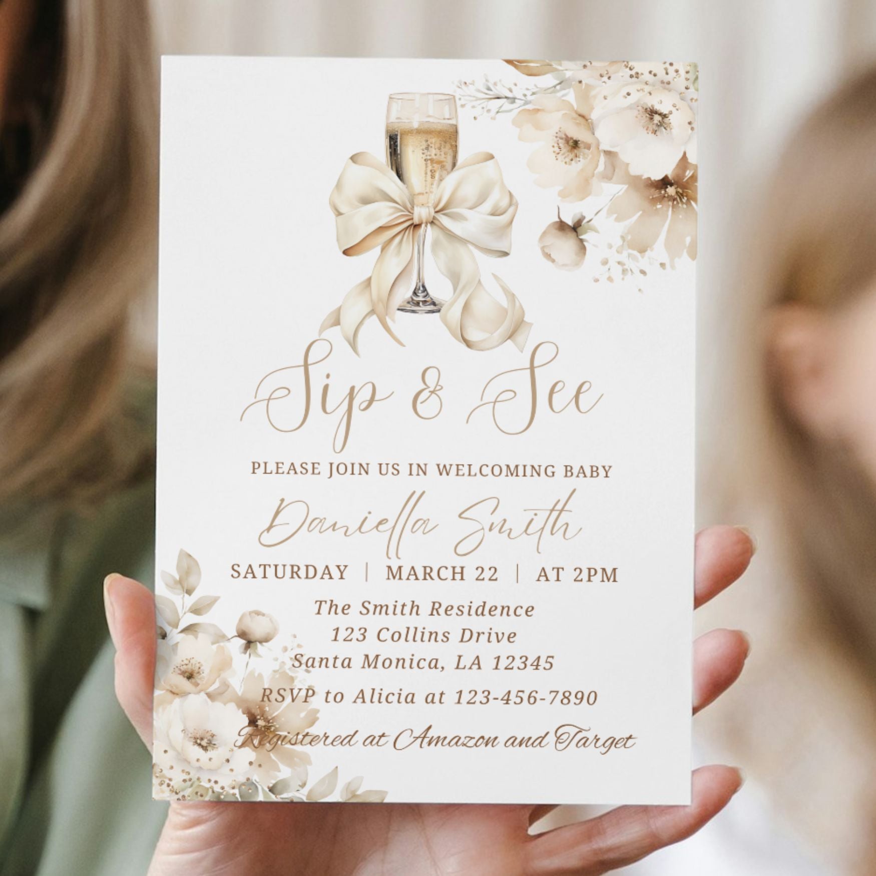 Invitation card with champagne glass, bow, and floral design held by a person.