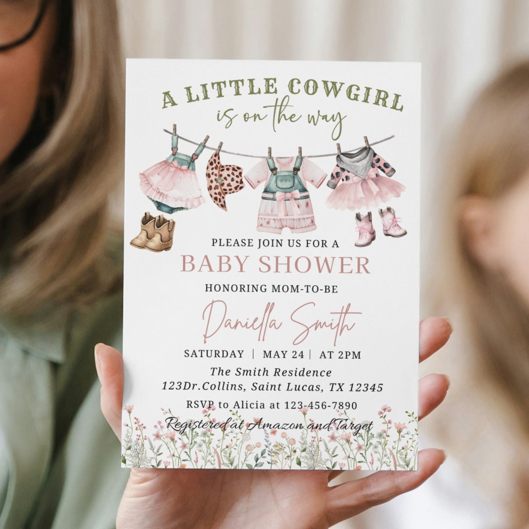 Baby shower invitation for a little cowgirl with baby clothes and boots on a line, held by a person.