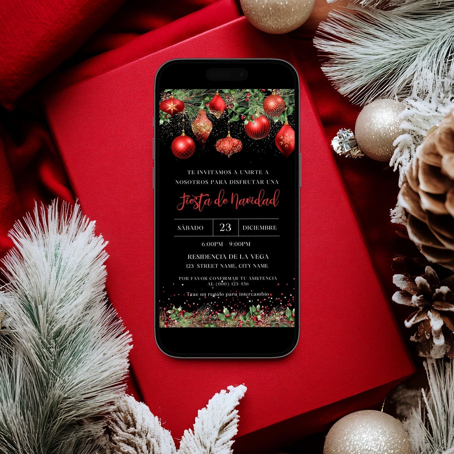 Phone displaying a Spanish Christmas party invitation on a red surface with festive decorations.