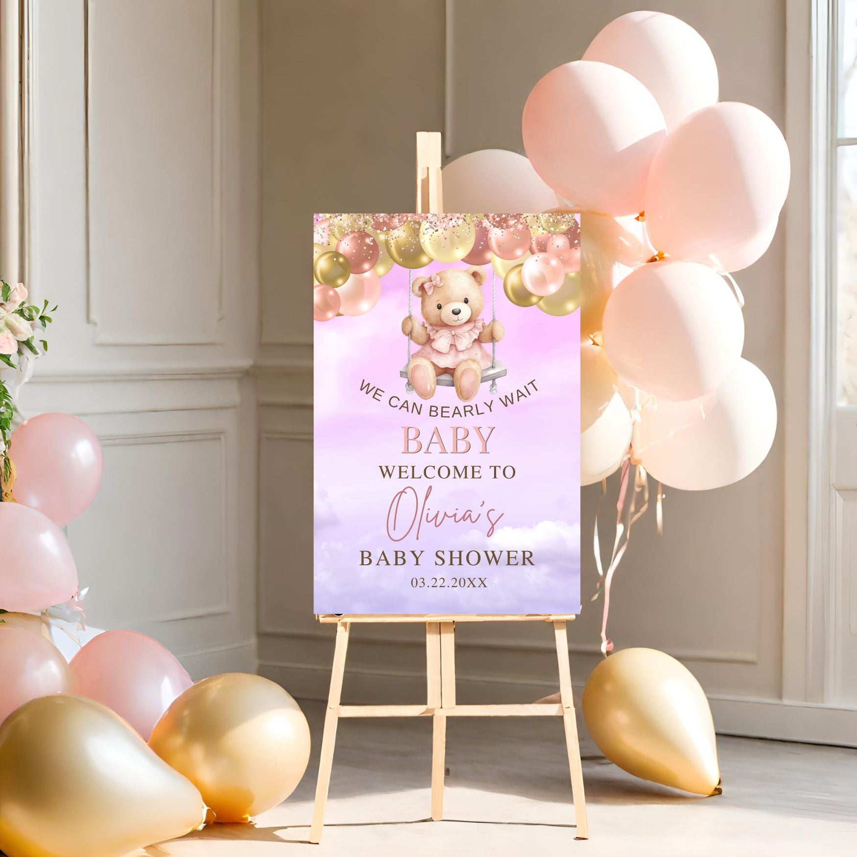 Baby shower invitation with teddy bear design on an easel surrounded by balloons.