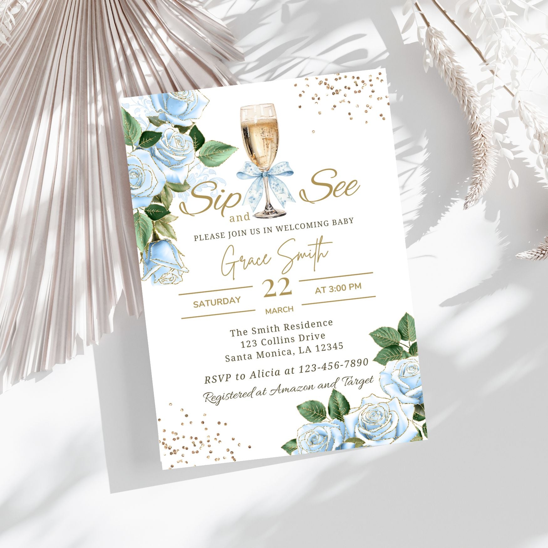 Baby shower invitation with champagne glass, blue flowers, and greenery on a white background.