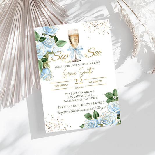 Baby shower invitation with champagne glass, blue flowers, and greenery on a white background.
