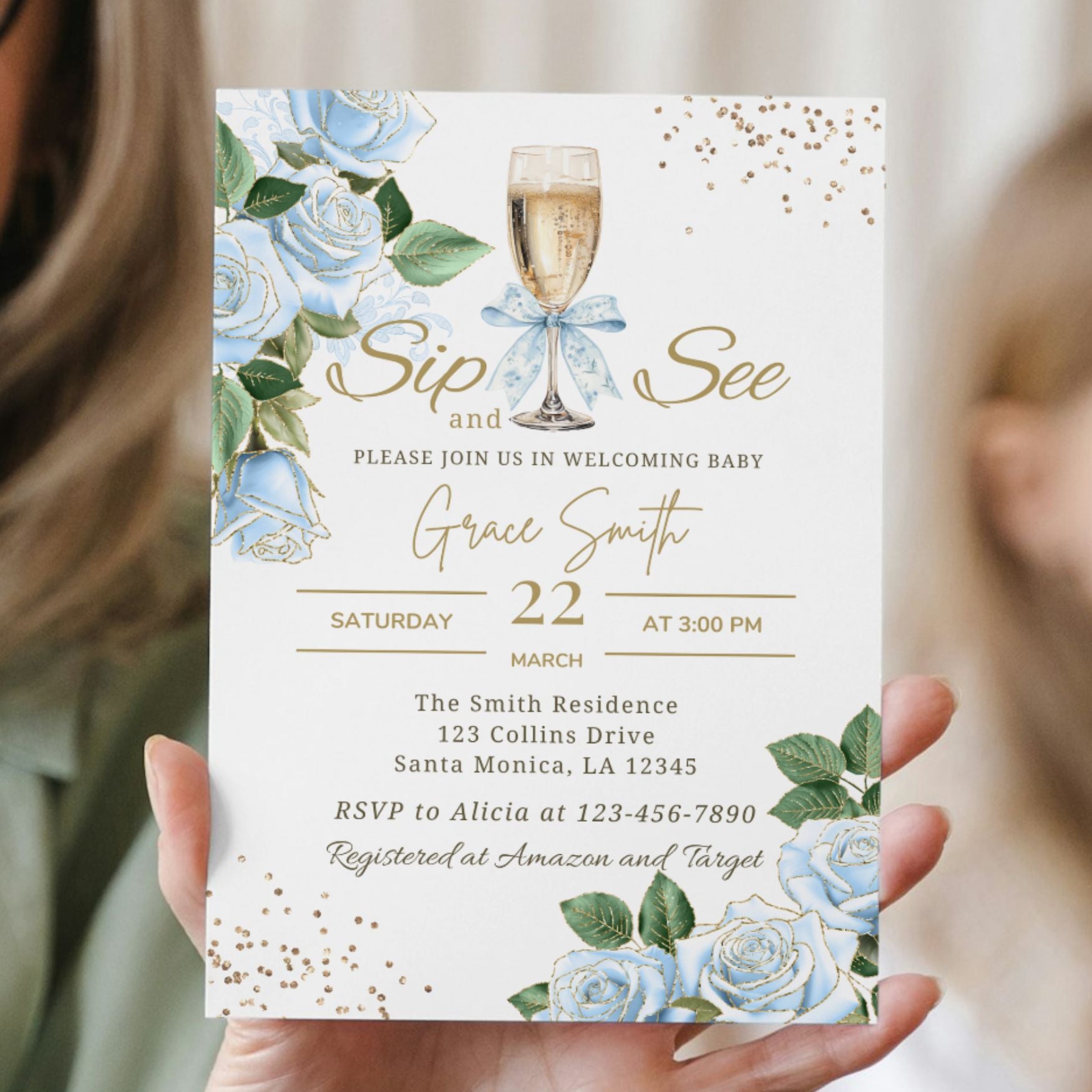 Baby shower invitation with champagne glass and blue flowers held by a person